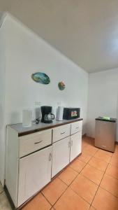 una cocina con armarios blancos y platos en la pared en Monteverde River House, en Monteverde