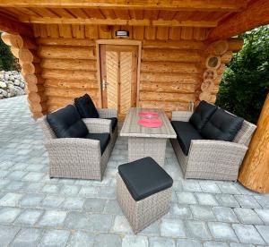 a patio with two wicker chairs and a table at Zrubový Dom 1 v Panoráma Parku in Nezbudská Lúčka