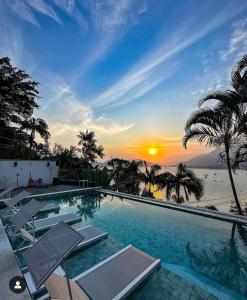 uma piscina com cadeiras e um pôr-do-sol ao fundo em Catalina Hotel em Ubatuba