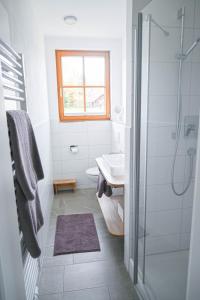 a white bathroom with a shower and a sink at Gästehaus Alpenruh in Fischen