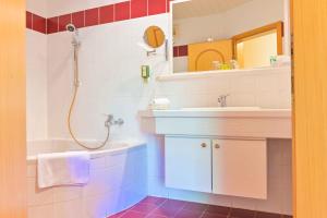 ein Bad mit einer Badewanne, einem Waschbecken und einer Dusche in der Unterkunft Ferienhotel Alber in Mallnitz