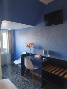 a blue room with a table and two chairs at Hôtel Le Phare in Ouistreham