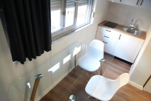 uma pequena cozinha com uma mesa de vidro e 2 cadeiras brancas em Be Solei Studio Apartments Sol 1 em Tirana