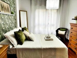 1 dormitorio con cama con almohadas verdes y espejo en Hoibai, Apt Bolboreta, elegante, céntrico, cómodo, en Baiona