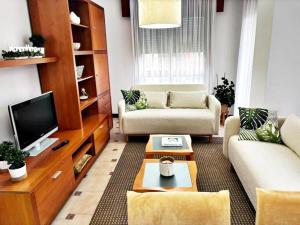 a living room with two couches and a tv at Hoibai, Apt Bolboreta, elegante, céntrico, cómodo in Baiona