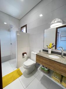 uma casa de banho com um WC, um lavatório e um espelho. em Toledo Home, Trancoso em Trancoso