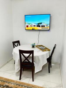 une table blanche avec des chaises et une télévision murale. dans l'établissement Maragoli Retreat, à Midrand