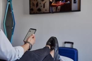 une personne assise sur une chaise tenant un téléphone portable dans l'établissement One Morelia Acueducto, à Morelia