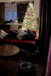 a christmas tree in a living room with a red couch at Boutique Villa Gyula in Gyula