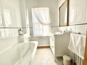 a white bathroom with a tub and a sink at Green Cottages in Sittingbourne