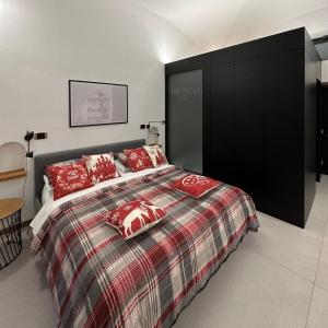 1 dormitorio con 1 cama grande con almohadas rojas en Dislocati BnB - Jacuzzi privata - Cucina - TV60" - Minimal Luxury, en Marigliano