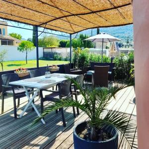 eine Terrasse mit einem Tisch, Stühlen und einem Sonnenschirm in der Unterkunft Gîtes, maisonnette de charme in Crestet