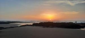 una puesta de sol sobre el océano con la puesta de sol en Cave's on to the beach, en Douaïra