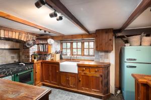 a kitchen with wooden cabinets and a blue refrigerator at Traditional Cornish Cottage in the Countryside. in Gwinear