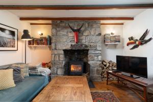 a living room with a couch and a stone fireplace at Traditional Cornish Cottage in the Countryside. in Gwinear