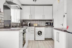 uma cozinha com armários brancos e uma máquina de lavar roupa em Sunny 3 Bedroom House in Vibrant Brighton with PARKING & FAST INTERNET em Brighton & Hove