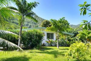 a white house with palm trees in the yard at TAHAA - Fare Motoi in Tiva