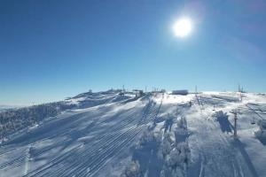 Una colina cubierta de nieve con el sol encima. en Ski hotel DOBRODOLAC en Kopaonik