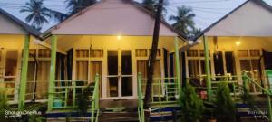 a house with green and white doors and trees at SUNBATH beach EXOTICA in Canacona