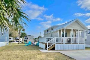 a white house with a porch and a yard at Vacation Cottages in North Myrtle Beach 66 in Myrtle Beach