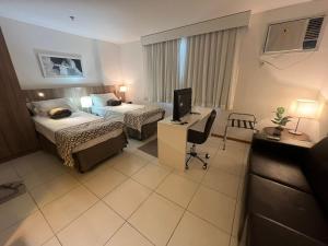 una camera d'albergo con 2 letti e una scrivania con un computer di Terra Hospedagem Apartamento luxuoso Soho a Campos dos Goytacazes