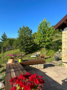 una panchina di legno con fiori rossi in giardino di Little Garden cabin a Perivolaki
