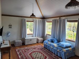 a bedroom with a bed and windows and a rug at Casa Corumbau temporada Recanto Ipê-Amarelo a 400m da praia in Corumbau