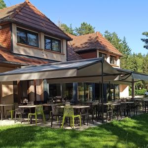 restauracja ze stołami i krzesłami pod baldachimem w obiekcie Hôtel Restaurant Logis La Méridienne w mieście Anglards-de-Saint-Flour