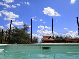 a swimming pool with a bench and a blue sky at Campo de los Zorros in Nono