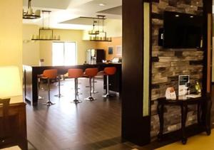 a living room with a bar with chairs and a table at Comfort Inn & Suites Woodward in Woodward