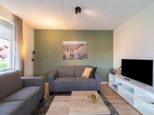 Una sala de estar con un sofá y un televisor. en Cozy Retreat with parking, en Scherpenisse