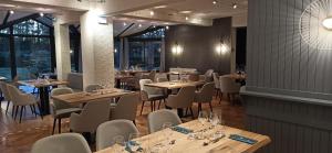 a restaurant with wooden tables and chairs and windows at Hôtel Restaurant Logis La Méridienne in Anglards-de-Saint-Flour