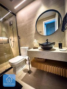 a bathroom with a sink and a toilet and a mirror at Apartamento de luxo na Barra com vista mar in Salvador