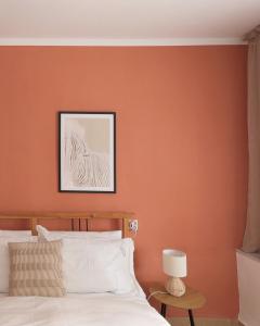 a bedroom with an orange wall with a bed and a lamp at Garden House Retreat in Drama