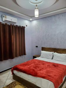 a bedroom with a bed with a red blanket at Residence Adnan luxury Appartments in Ouarzazate