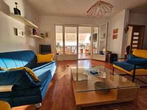 a living room with a blue couch and a glass table at Beachfront First Line View in Sveti Stefan