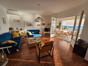 a living room with blue furniture and a view of the ocean at Beachfront First Line View in Sveti Stefan