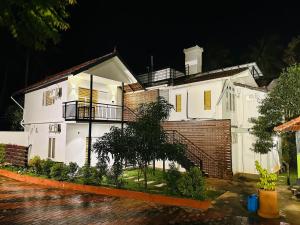 a white house at night with a brick wall at Farm Fort Resort By Luxdens Hotels in Kozhikode