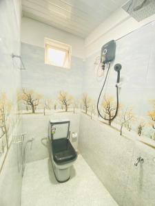 baño con aseo y ducha con árboles en la pared en Minuki guest house, en Weligama