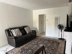 un sofá de cuero negro en una sala de estar con alfombra en Beautiful 1BD apartment, en Los Ángeles