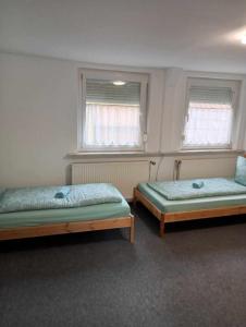 two beds in a room with two windows at Andrei Ferienwohnung in Marktbreit