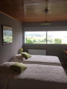 a bedroom with two beds and a large window at Les genêts in Saint-Alban-sur-Limagnole