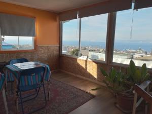 Habitación con mesa, sillas y ventanas. en Hostal Armando, en Valparaíso
