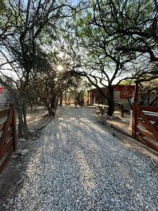 uma estrada de cascalho com árvores e uma cerca em Jardin de Estrellas em San Marcos Sierras