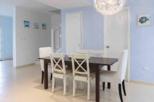 a dining room table with white chairs and a chandelier at VIlla Caracol in Punta Cana