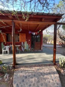 a house with a wooden pergola with a table at Jardin de Estrellas in San Marcos Sierras