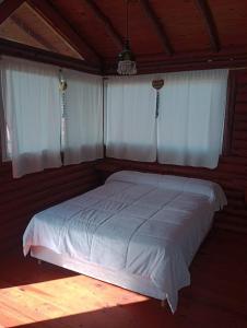 a bedroom with a bed with white sheets and two windows at DOS NOGALES in San Pedro