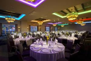 um salão de banquetes com mesas e cadeiras brancas e lustres em Eldorado Hotel and Spa em Santa Fé