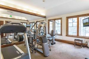 een fitnessruimte met loopbanden en crosstrainers in een kamer met ramen bij Saddleridge Villas #3 in Beaver Creek