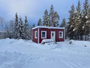 una pequeña casa roja en la nieve con árboles en Fjällkåken en Idre